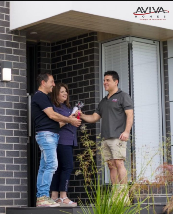 Hand over of keys with clients at front doorstep at end of custom home build